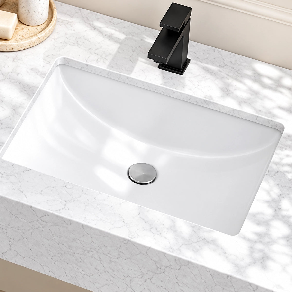 Close-up of a white engineered stone bathroom sink with an integrated basin, black single-hole faucet, and marble-look countertop.
