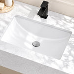 Close-up of a white engineered stone bathroom sink with an integrated basin, black single-hole faucet, and marble-look countertop.