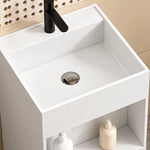 Close-up of a white engineered stone square bathroom sink with an integrated basin, single-hole black faucet, and open storage shelf.