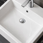 Close-up of a white ceramic semi-recessed bathroom sink with a rectangular basin, integrated overflow, and chrome single-hole faucet.