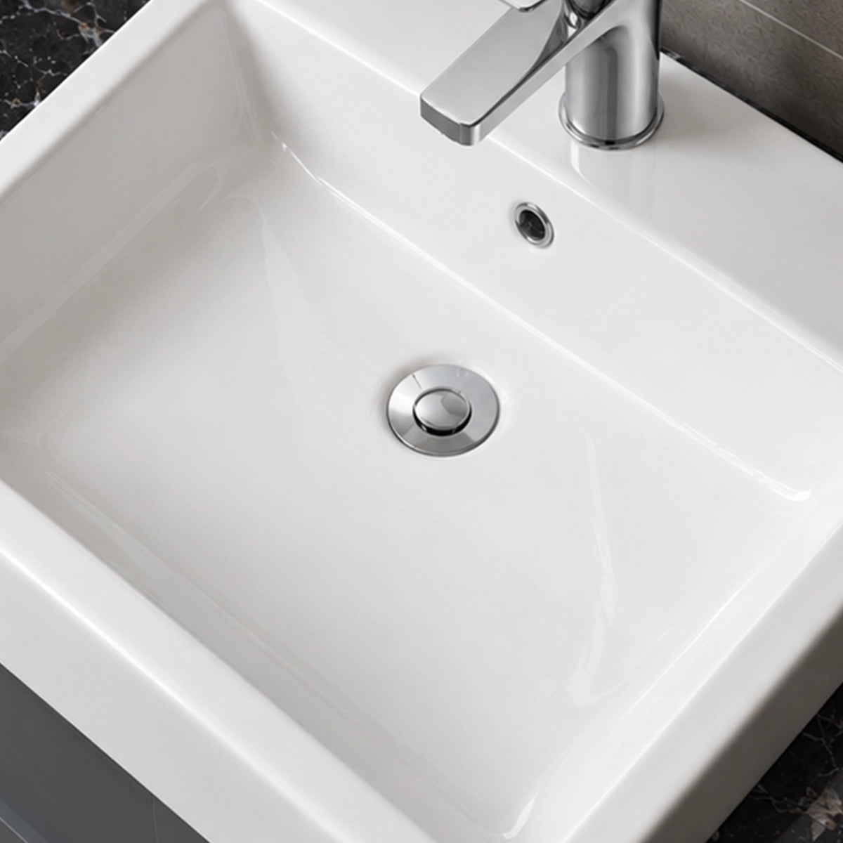 Close-up of a white ceramic semi-recessed bathroom sink with a rectangular basin, integrated overflow, and chrome single-hole faucet.