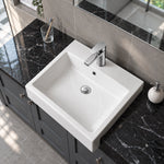 White ceramic semi-recessed bathroom sink with a rectangular basin, single-hole faucet, and integrated overflow on a dark vanity countertop.