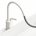 White horizontal pull-out faucet with a flexible braided hose and cylindrical base for a ceramic semi-recessed bathroom sink.