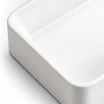 Close-up of the white ceramic semi-recessed bathroom sink showing its smooth glossy finish, rounded corner, and gently curved basin edge.