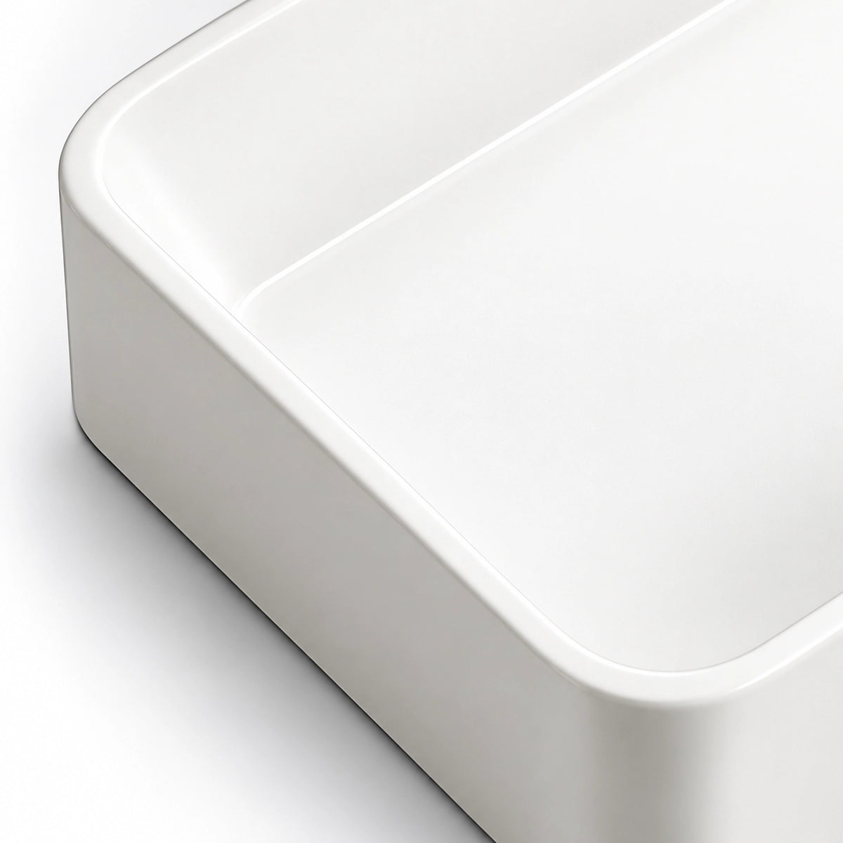 Close-up of the white ceramic semi-recessed bathroom sink showing its smooth glossy finish, rounded corner, and gently curved basin edge.